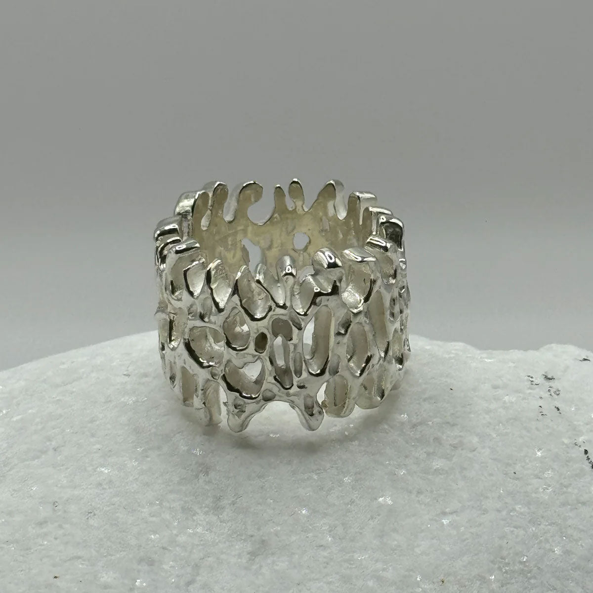Silver ring with a textured design on a gray background