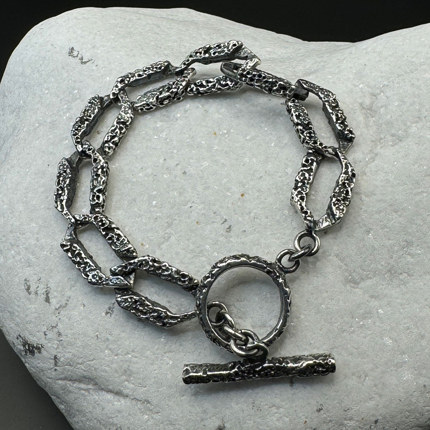 Silver chain bracelet with a clasp on a stone surface